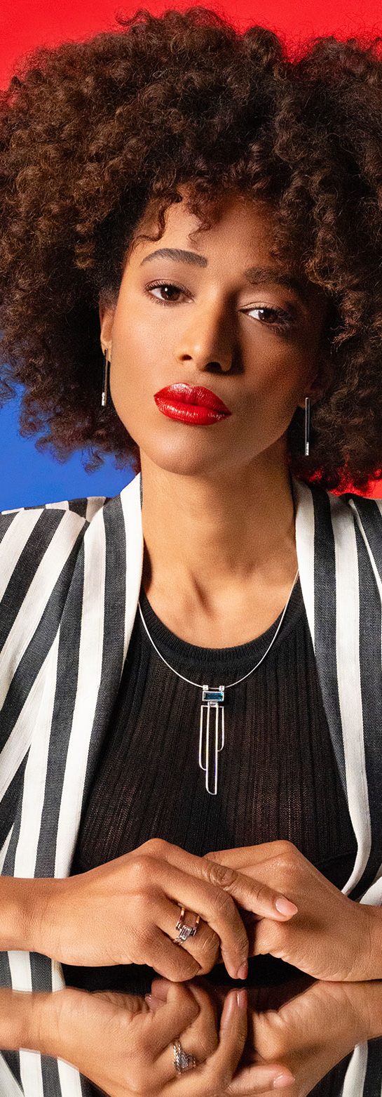 Fashion portrait of a woman in a striped blazer against blue and red